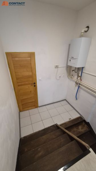 Schodiště s dřevěnými stupni a plynovým kotlem v 2pokojovém bytě.