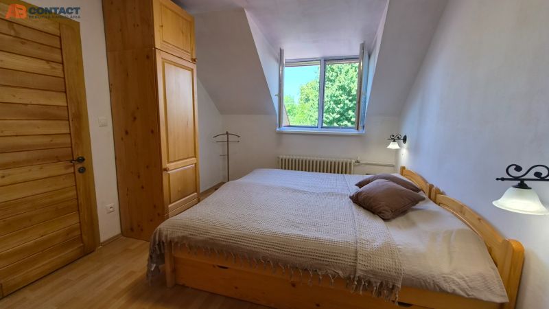 Ložnice s dřevěným nábytkem a podlahou s dřevěným dekorem ve 2-pokojovém bytě.