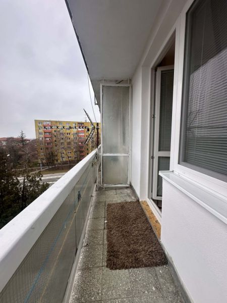 Balkon s kobercovou rohoží v Rekreačním apartmánu Dunajské Stredy, výhled na sídliště.