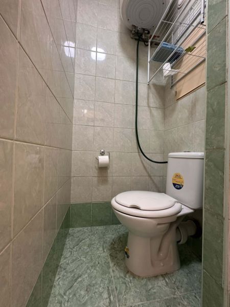 Toaleta v rekreačním apartmánu s obkladem do poloviny stěny, zelené dlaždice.