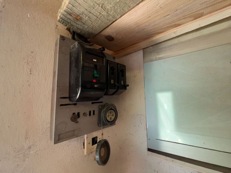 Stará elektrická rozvodná skříň v garáži, se starými jističemi a zásuvkami.