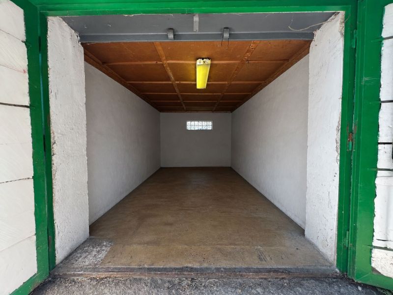 Otevřená garáž s dřevěným stropem a betonovou podlahou.