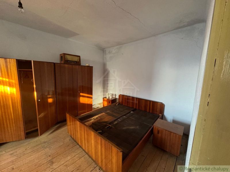 Ložnice s retro nábytkem a podlahou s dřevěným dekorem v rodinném domě.