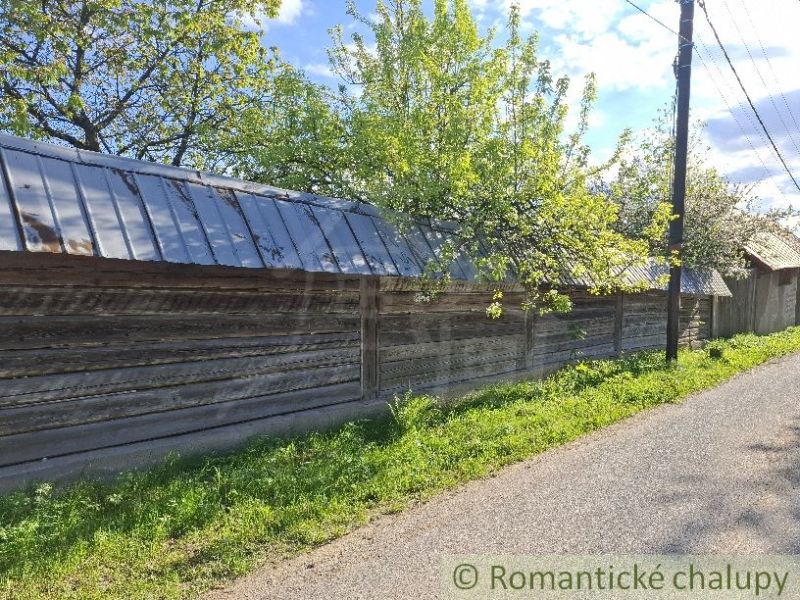 Dřevěné oplocení u rodinného domu v Šumiaci, obklopené stromy a cestou.