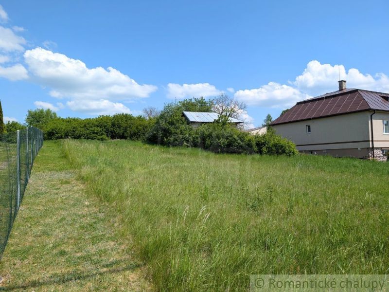 Travnaté pozemky na bydlení v Karnej s výhledem na dům a modrou oblohu.