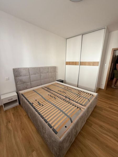Ložnice s postelí, skříní a podlahou s dřevěným dekorem v 2-pokojovém bytě.