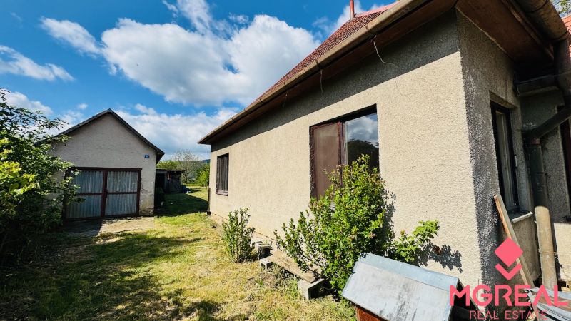 Rodinný dům v Pažiti se zahradou a samostatnou garáží pod modrou oblohou.