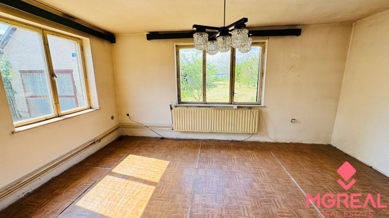 Pokoj v rodinném domě s podlahou s dřevěným dekorem a velkými okny.