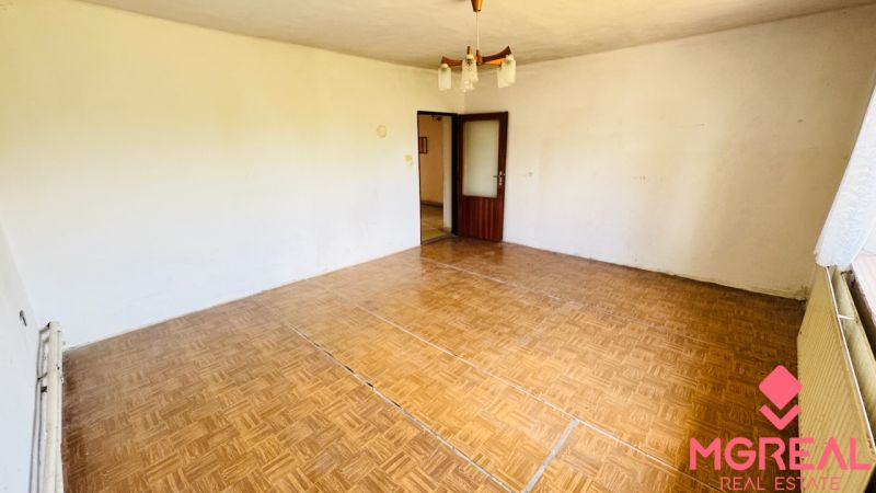 Pokoj v rodinném domě s podlahou s dřevěným dekorem a lustrem.
