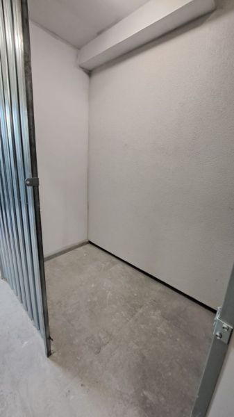 Malé skladové prostory s kovovými dveřmi a betonovou podlahou v 2-pokojovém bytě.