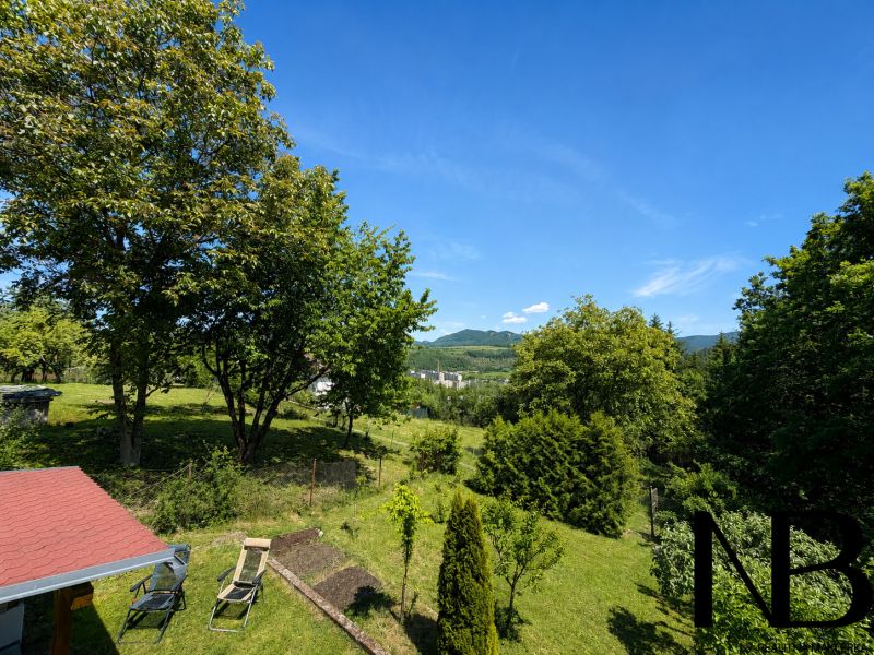 Zahrada chaty na Klučině v Považské Bystrici s bohatou zelení a židlemi.