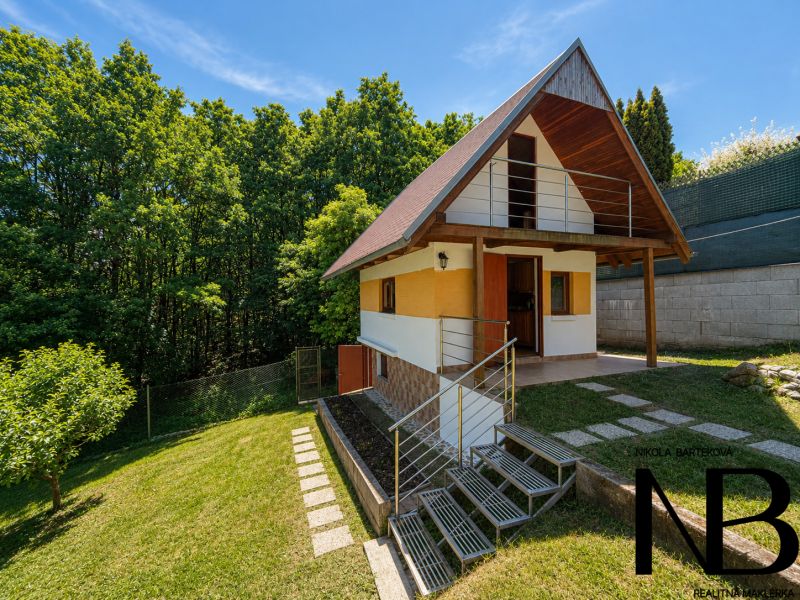 Chata s dřevěným dekorem v Považské Bystrici na Klučině, obklopená zelení a stromy.