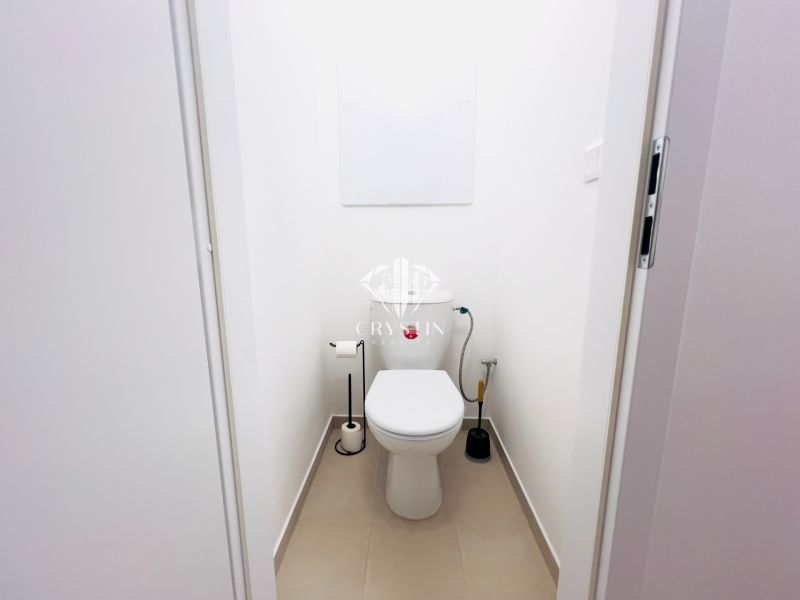 Toaleta s bílými stěnami v 2-pokojovém bytě, jednoduché sanitární vybavení.