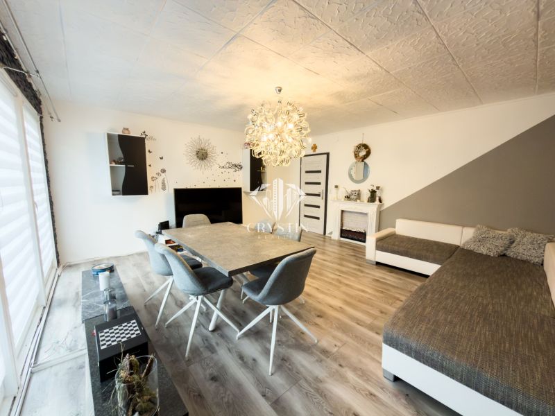 Obývací pokoj v rodinném domě s podlahou s dřevěným dekorem a elegantním osvětlením.