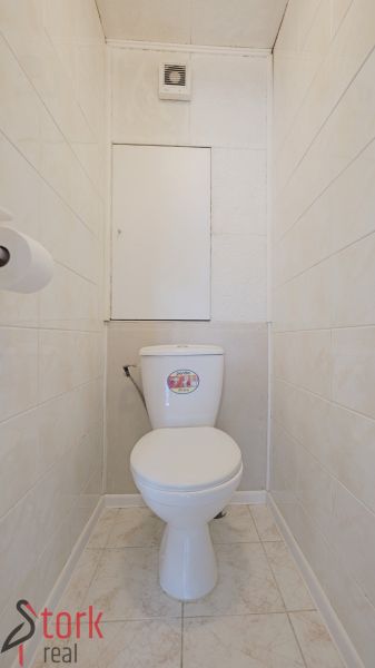 Koupelna třípokojového bytu s bílými dlaždicemi a toaletou.