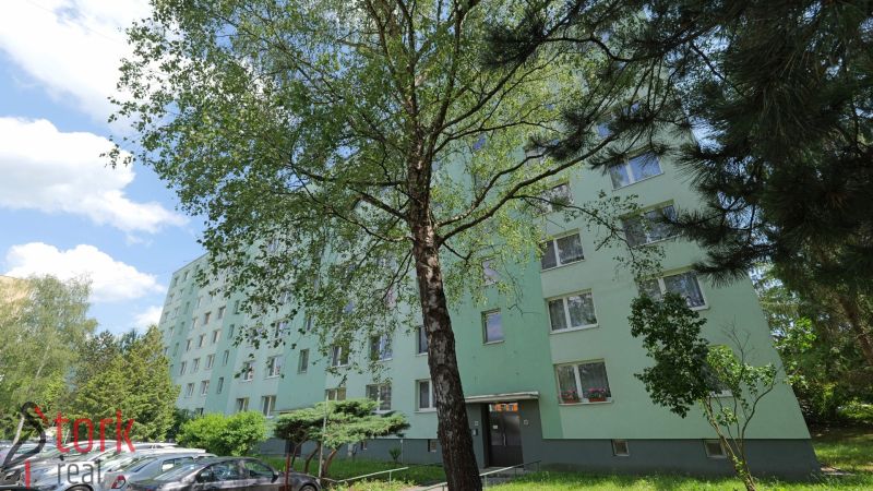 Považská Bystrica, Štúrova: Panelový dům obklopený stromy a zaparkovanými auty na ulici.