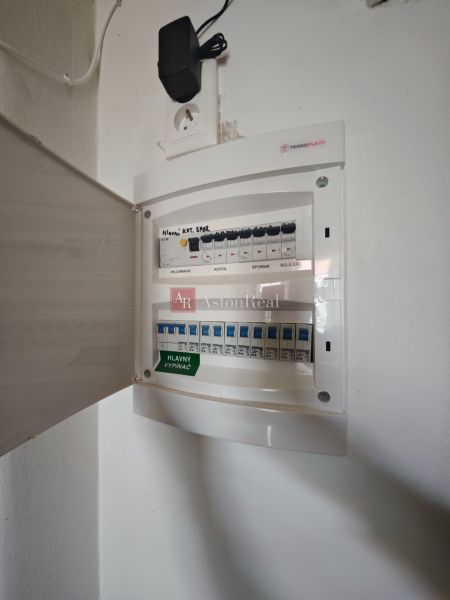 Elektrická rozvodná skříň v 2-pokojovém bytě s otevřenými dvířky a zásuvkou.