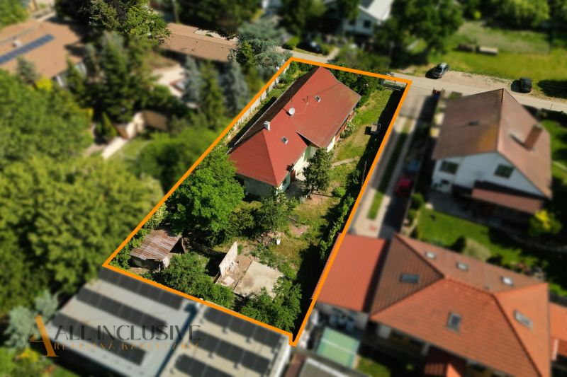 Rodinný dům v Hviezdoslavově s červenou střechou, obklopený zelení a dalšími stavbami.