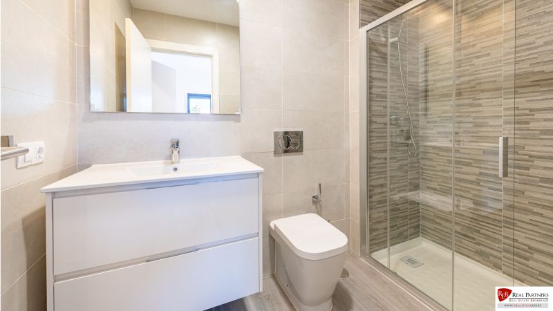 Koupelna v rekreačním apartmánu s velkým sprchovým koutem a elegantním umyvadlem.