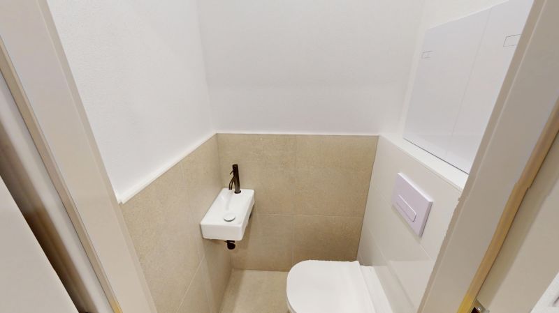 Toaleta v 2-pokojovém bytě s umyvadlem a bílou stěnou.