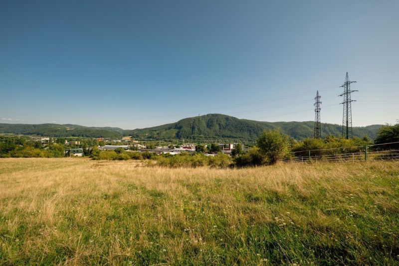 Krajina s travnatým pozemkem a elektrickými sloupy na Partizánské cestě, Banská Bystrica. Pozemky - bydlení.