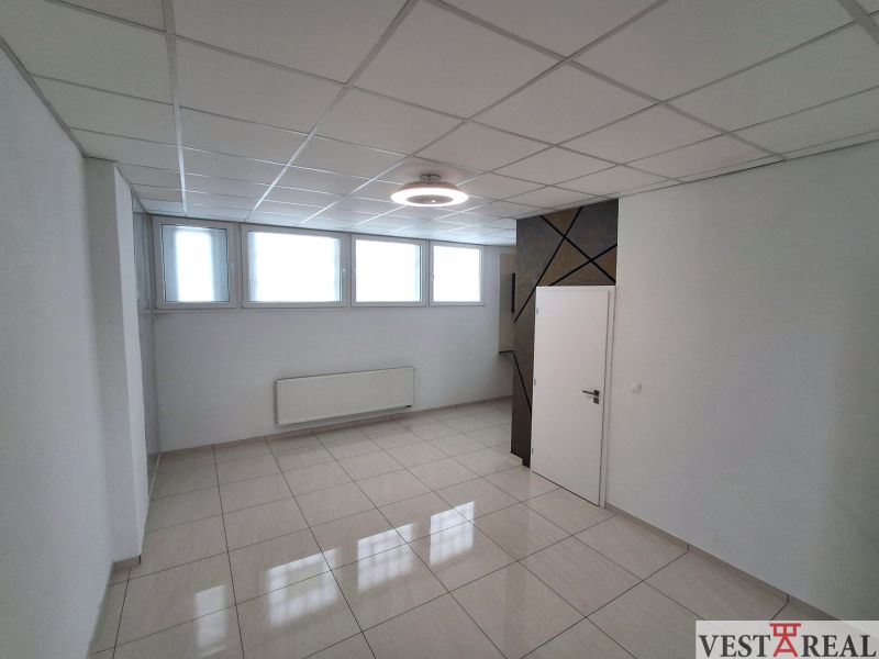 Kanceláře se světlou dlažbou, bílými stěnami a okny, jednoduchý stropní design.