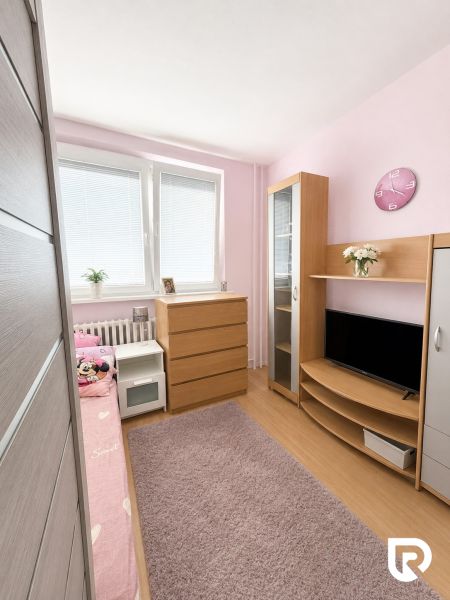 Dětský pokoj s podlahou s dřevěným dekorem, růžovými stěnami a dřevěným nábytkem ve 3-pokojovém bytě.