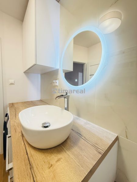 Koupelna v 3-pokojovém bytě s designovým umyvadlem a osvětleným zrcadlem.