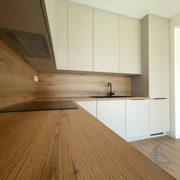 Kuchyně v rodinném domě s elegantní podlahou s dřevěným dekorem a bílými skříňkami.