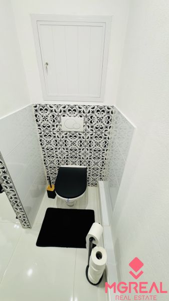 Toaleta s černobílým kachličkovým vzorem v 1-pokojovém bytě.