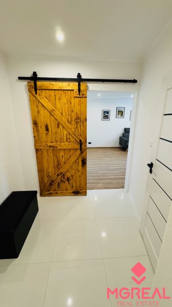 Interiér s posuvnými dřevěnými dveřmi vedoucími do 1-pokojového bytu s podlahou s dřevěným dekorem.