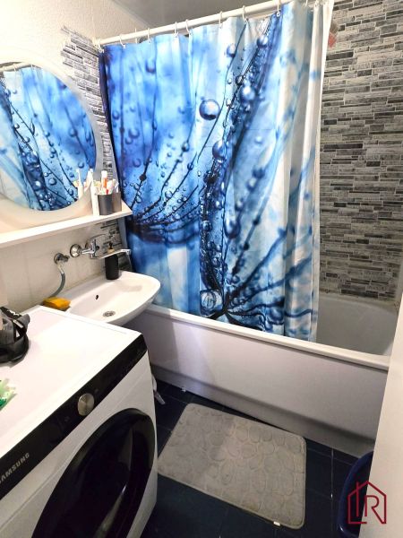 Koupelna se sprchovým závěsem, umyvadlem a pračkou ve 4-pokojovém bytě.