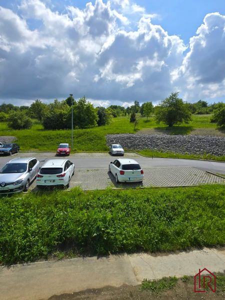 Parkoviště s auty na Ďumbierské ulici v Prešově obklopené zelení a oblohou.