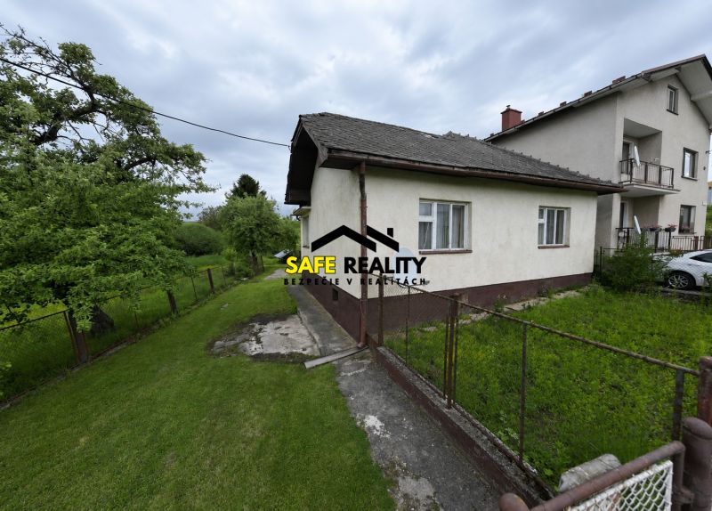 Rodinný dům v Žilině s upravenou zahradou a plotem, obklopený přírodou.