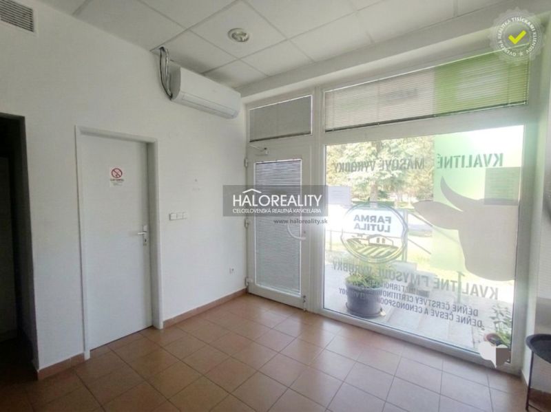 Obchodní prostory s dlažbou, klimatizací a moderními prosklenými dveřmi.