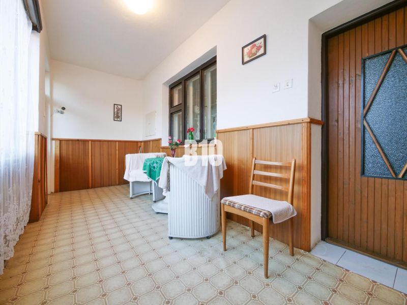Chodba v rodinném domě s židlí a stolem, obložení stěnami ze dřeva.
