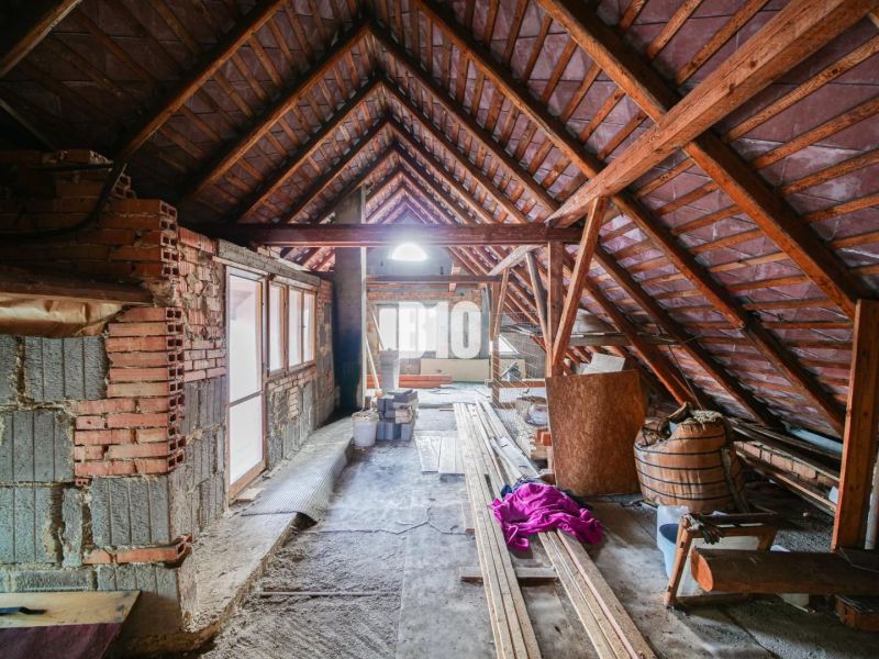 Půda rodinného domu s rozestavěnými zdmi a dřevěnou konstrukcí střechy.