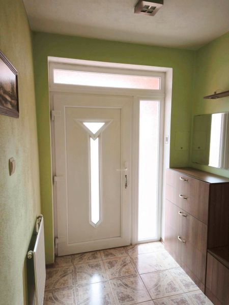 Vstupní dveře v Rodinném domě s bílým rámem a dlažbou s dekorem.