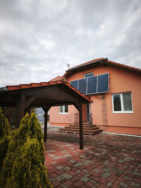 Rodinný dům v Martin nad Žitavou se solárními panely a altánem na terase.