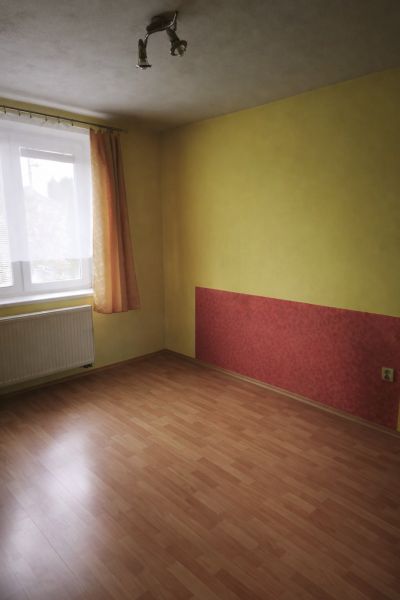 Pokoj v rodinném domě s podlahou s dřevěným dekorem a barevnou stěnou.