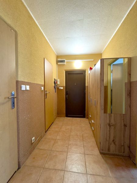 Chodba se skříněmi ve 4-pokojovém bytě s dlažbou a dřevěnými dveřmi.