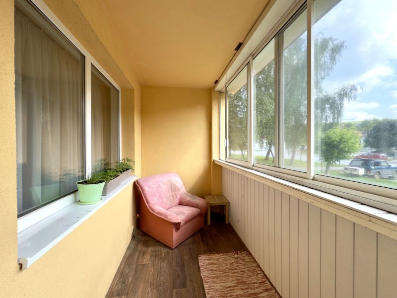 Balkon 4pokojového bytu s posezením a podlahou s dřevěným dekorem.