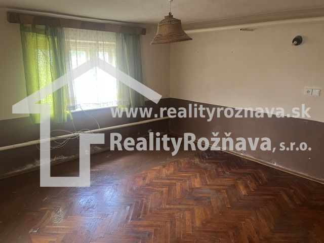 Pokoj v rodinném domě s podlahou s dřevěným dekorem a zelenými závěsy.