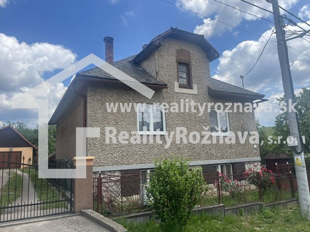 Rodinný dům v Rudné s dvoupatrovou fasádou, oploceným pozemkem a modrou oblohou.