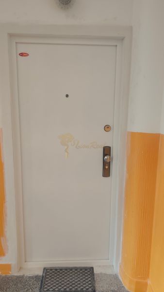 Bílé dveře na chodbě 4-pokojového bytu s oranžovými stěnami.