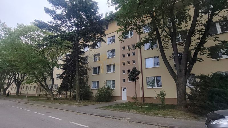 Bytový dům na Exnárově ulici v Bratislavě - Ružinově obklopený stromy.