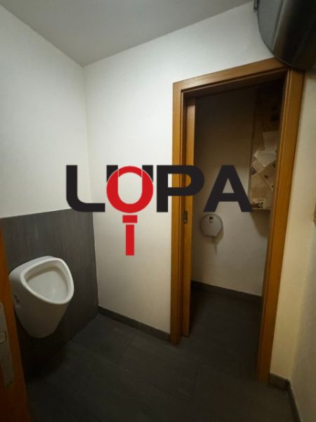 Interiér obchodních prostor s toaletou a tmavou podlahou s dřevěným dekorem.