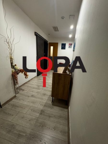 Úzká interiérová chodba s podlahou s dřevěným dekorem, dekorací a dveřmi.