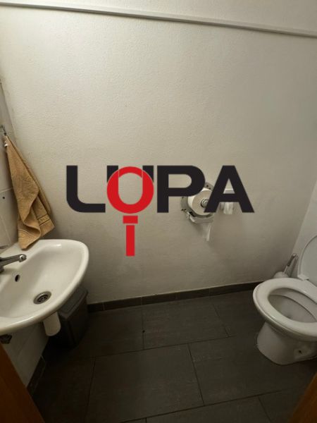 Toaleta s umyvadlem a dlažbou. Obchodní prostory s jednoduchým vybavením.