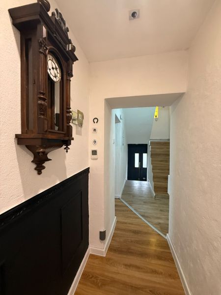 Chodba rodinného domu s hodinami a podlahou s dřevěným dekorem.